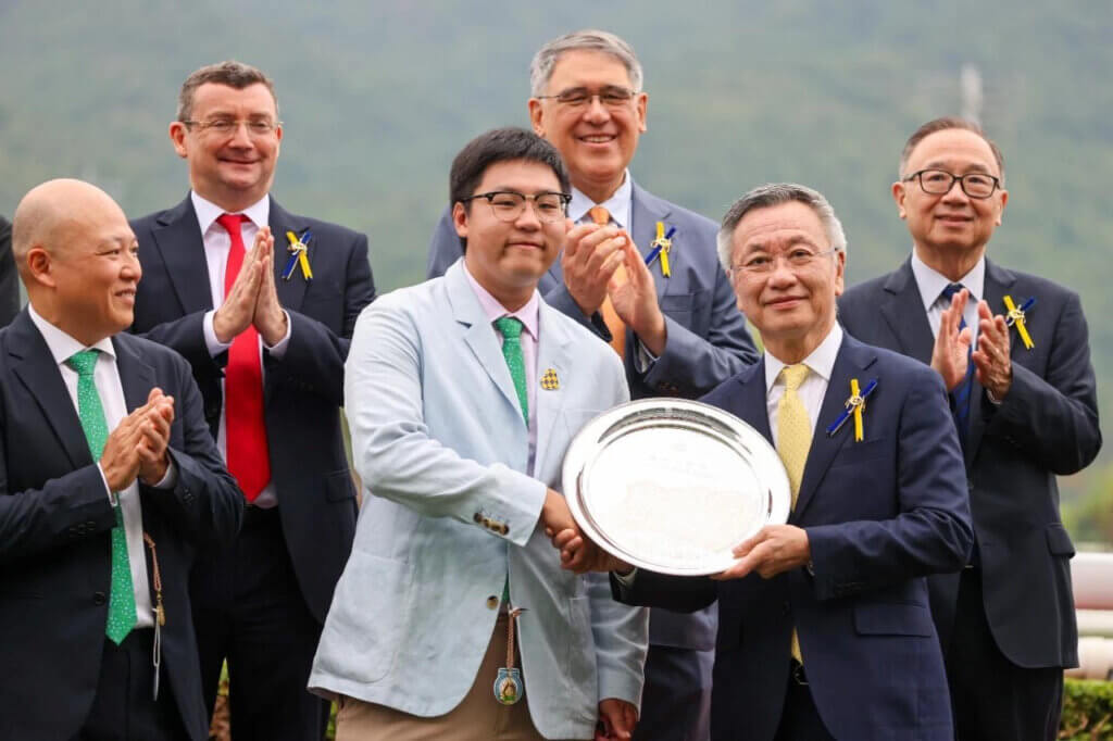 Alex So holding the trophy alongside father Chris
