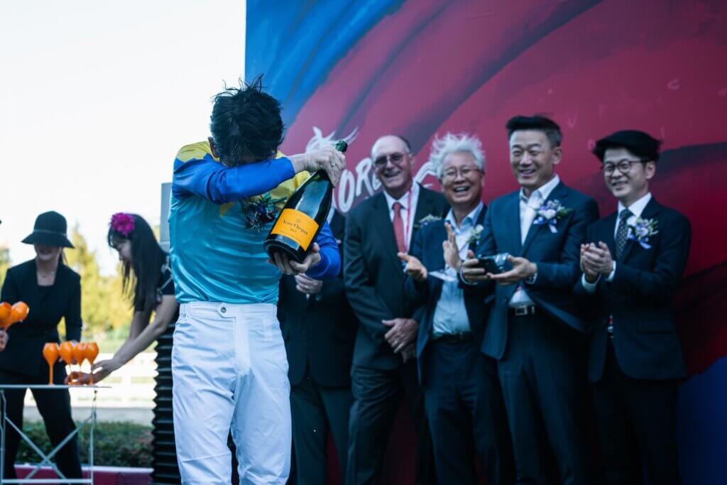 Tosaki wiping champagne from his eyes in Korea